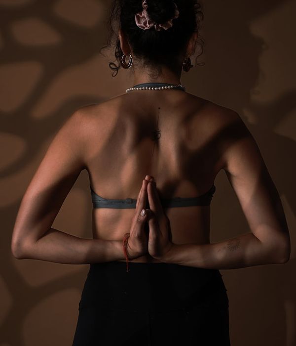 Woman performing a fluid yoga pose in a calm dark studio.